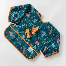 Load image into Gallery viewer, Bumkins Sleeved Bib: Jungle lays on a white background with orange baby utensils on top.
