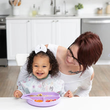 Load image into Gallery viewer, A smiling woman and toddler enjoy a meal at a white table; the toddler wears a white bow and a Bumkins Sleeved Bib: Floral.
