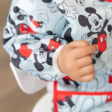 Load image into Gallery viewer, Close-up of a child wearing a Bumkins Sleeved Bib: Mickey Mouse, with focus on the elastic cuff on the sleeve.
