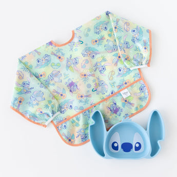 Bumkins Sleeved Bib: Aloha Stitch lays next to a Stitch-shaped silicone plate on a white background.