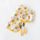 Bumkins Sleeved Bib: Winnie Loves Hunny lays folded on a white background with a yellow fork and spoon.