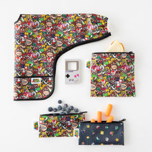 Load image into Gallery viewer, Bumkins Sleeved Bib: Super Mario™ Mashup lays folded on a white background next to matching pouches with snacks &amp; a GameBoy-shaped teether.
