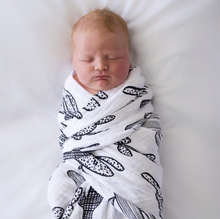 Load image into Gallery viewer, A newborn rests on a soft white surface in a high-contrast Modern Burlap Organic Swaddle, Cactus.
