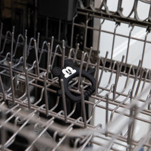 Load image into Gallery viewer, Bumkins Silicone Flat Teether: Mickey Mouse sits in the top rack of an open dishwasher.
