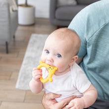 Load image into Gallery viewer, A blue-eyed baby enjoys the Bumkins Silicone Flat Teether: Winnie the Pooh, soothing gums while snuggled on a lap indoors.
