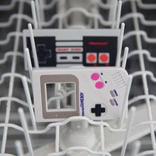 Load image into Gallery viewer, Bumkins Silicone Teether: NES™ Controller  sits behind another teether in the top rack of an open dishwasher.
