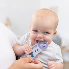 Load image into Gallery viewer, A baby is playfully biting a Bumkins Silicone Teether: Nintendo SNES™ Controller while held by someone with blue-painted nails.
