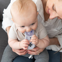 Load image into Gallery viewer, A baby joyfully chews a Bumkins Silicone Teether: Nintendo SNES™ Controller for ultimate gum relief on a woman's lap.
