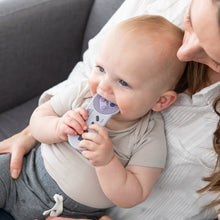 Load image into Gallery viewer, A baby chews a Bumkins Silicone Teether: Nintendo SNES™ Controller while sitting on an adult's lap on a gray couch.
