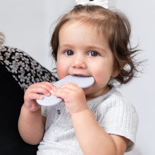 Load image into Gallery viewer, A brown-haired toddler in a light gray shirt chews on a Bumkins Silicone Teether: Nintendo SNES™ Controller for gum relief.
