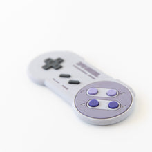 Load image into Gallery viewer, Bumkins Silicone Teether: Nintendo SNES™ Controller, featuring a gray body and purple buttons, on white background.
