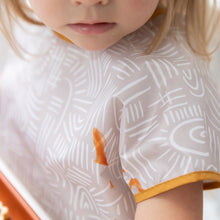 Load image into Gallery viewer, Close-up of a child wearing a Bumkins Junior Bib: Wander with a stain, highlighting the importance of its waterproof fabric.
