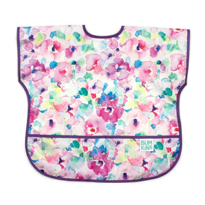 Bumkins Junior Bib: Watercolor features colorful floral watercolor patterns on waterproof fabric, purple trim, and front pocket.