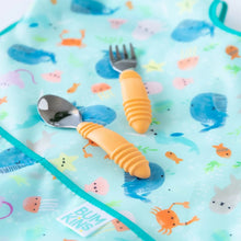 Load image into Gallery viewer, Close-up of an orange spoon and fork on top of a Bumkins Junior Bib: Ocean Life.
