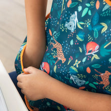 Load image into Gallery viewer, Close-up of a child wearing a Bumkins Junior Bib: Jungle, reaching into the pocket.
