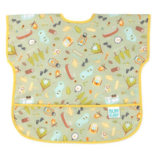 Load image into Gallery viewer, Bumkins Junior Bib: Camp Gear features camping illustrations on green waterproof fabric with a yellow trim and front pocket.
