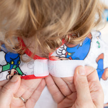 Load image into Gallery viewer, Close-up of hands fastening the hook-and-loop closure of Bumkins Junior Bib: Super Mario™ &amp; Luigi around a child's neck.
