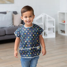 Load image into Gallery viewer, In a bright living room, a smiling child wears a Bumkins Junior Bib: Super Mario™ Lineup .
