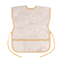 Load image into Gallery viewer, Bumkins Short-Sleeved Smock: Wander features beige waterproof fabric with a white abstract pattern, orange trim, adjustable ties and a pocket.
