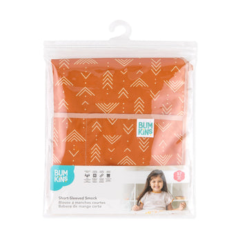 Bumkins Short-Sleeved Smock: Grounded is shown folded in plastic packaging bag with a hanger and cardboard insert.