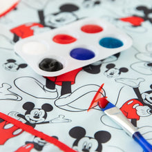 Load image into Gallery viewer, Close-up of a paintbrush with red paint on a Bumkins Short-Sleeved Smock: Mickey Mouse Classic, next to a paint palette.

