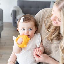 Load image into Gallery viewer, A baby with a white bow chews on the Bumkins Silicone Un-Droppable Mitt Teether: Winnie the Pooh while sitting on a woman's lap.
