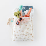 Bumkins Wet Bag: Palm Daze keeps sunglasses, toy palm tree, trunks, spade & towel dry with waterproof protection on a white background.