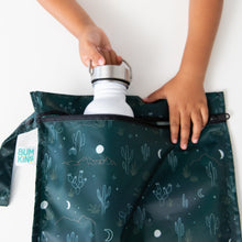 Load image into Gallery viewer, A child places a white water bottle into a Bumkins Wet Bag: Starry Cactus on a white table.
