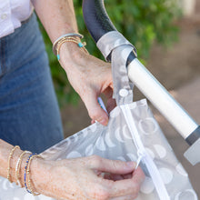 Load image into Gallery viewer, A person unzips a Bumkins Wet Bag: Lunar Phase attached to a stroller handle outdoors.
