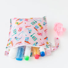 Load image into Gallery viewer, Travel-size toiletries and a hairbrush spill from an open Roamio by Bumkins Wet Bag: Boots on a white background.
