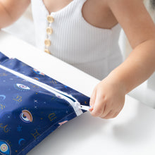 Load image into Gallery viewer, A child in a white top unzips a Bumkins Wet Bag: Evil Eye at a white table.
