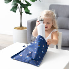 Load image into Gallery viewer, A child puts a bottle into Bumkins Wet Bag: Evil Eye at a white table.
