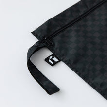 Load image into Gallery viewer, Close-up of Roamio by Bumkins Wet Bag: Rich Black on a white background, with focus on the side strap and logo tag.
