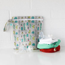 Load image into Gallery viewer, Bumkins Wet Bag: Cacti sits on a white table against a white brick wall with cloth diapers and breast pump parts in front.
