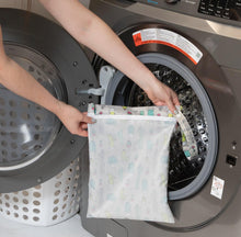 Load image into Gallery viewer, A person holds Bumkins Wet Bag: Cacti in front of an open front-loading washing machine.
