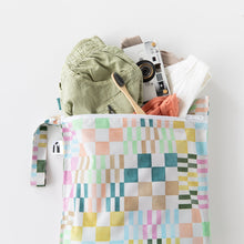 Load image into Gallery viewer, Roamio by Bumkins Wet Bag: Motley Check holds green shorts, clothes, a camera, and toothbrush on a white background.
