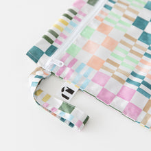 Load image into Gallery viewer, Close-up of Roamio by Bumkins Wet Bag: Motley Check on a white background, with focus on the zipper and side handle.
