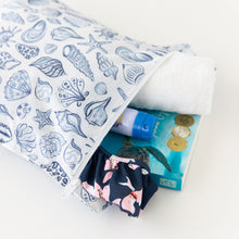 Load image into Gallery viewer, Roamio by Bumkins Wet Bag: Shells holds a towel, swimsuit, sunscreen, and book on a white background.
