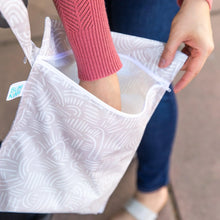 Load image into Gallery viewer, Close-up of a person wearing jeans and a pink sweater reaching into an open Bumkins Wet Bag: Wander.

