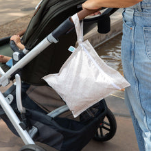 Load image into Gallery viewer, A person in jeans pushes a stroller with a Bumkins Wet Bag: Wander hanging from the handle.
