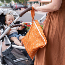 Load image into Gallery viewer, A woman in a brown dress pushes a stroller with a toddler and a Bumkins Wet Bag: Grounded hanging from the handle.
