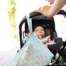 Load image into Gallery viewer, A person pushes a baby in a stroller with a Bumkins Wet Bag: Rainbows hanging from the handle.
