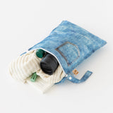 Bumkins Wet Bag: Vintage Denim lays open on a white background with a sweater, thermos, and book inside.