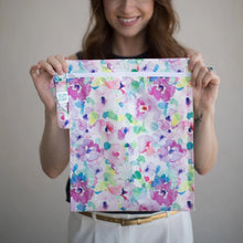 Load image into Gallery viewer, A person holds a Bumkins Wet Bag: Watercolor, standing in front of a light colored wall.
