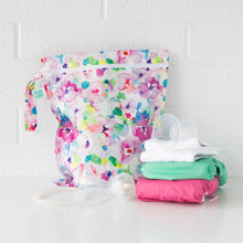 Load image into Gallery viewer, Bumkins Wet Bag: Watercolor sits on a white table against a white brick wall with cloth diapers and breast pump parts in front.
