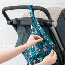 Load image into Gallery viewer, Hands unzip a Bumkins Wet Bag: Jungle, attached to a stroller handle with a white brick wall in the background.
