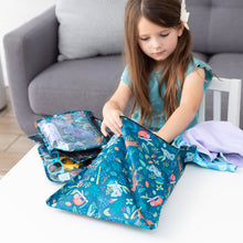 Load image into Gallery viewer, A girl reaches into a Bumkins Wet Bag: Jungle next to a stack of matching pouches and swim gear on a white table.
