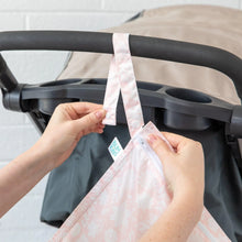 Load image into Gallery viewer, Hands attach a Bumkins Wet Bag: Lace to a stroller handle using the snap button on the strap.
