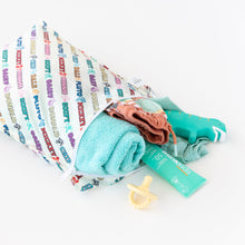 Load image into Gallery viewer, Bumkins Wet Bag: Mickey &amp; Friends Varsity is shown on a white background holding a pacifier, folded towel, clothing, and sunscreen.
