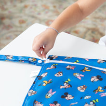 Load image into Gallery viewer, A child zips a Bumkins Wet Bag: Mickey &amp; Friends Forever on a white table.
